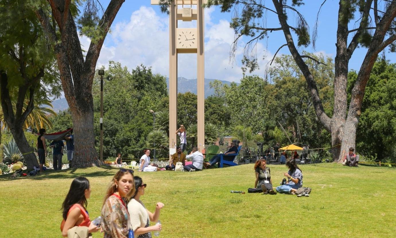 A Pitzer alum walks on a slackline in front of Brant Clock Tower